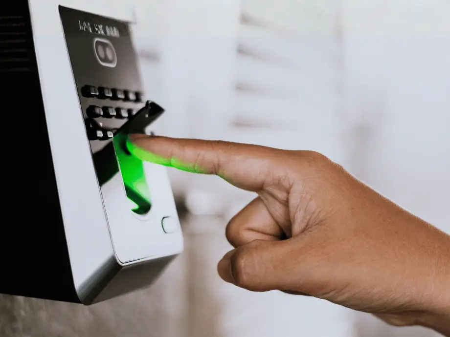 Persona apoyando el dedo en un lector biométrico de huella con luz verde para acceder a un área restringida de una empresa